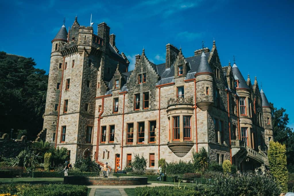 A large building with a garden in front of it with Belfast Castle in the backgro